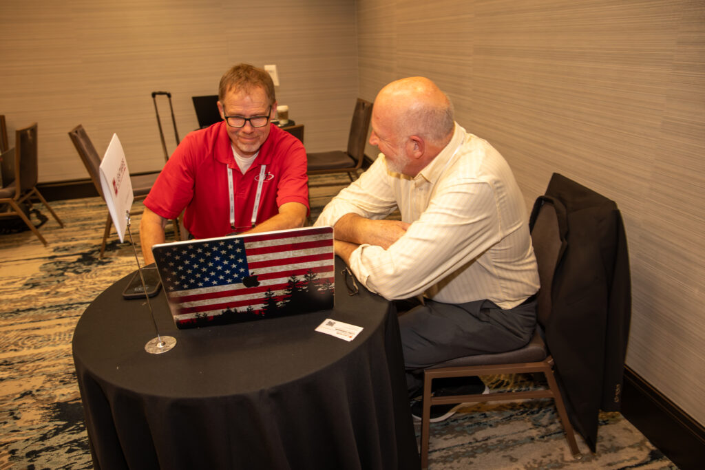 Two men sitting in front of a laptop